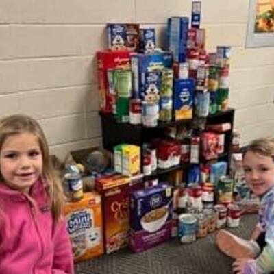 students showing off the donations their class collected in a food drive contest